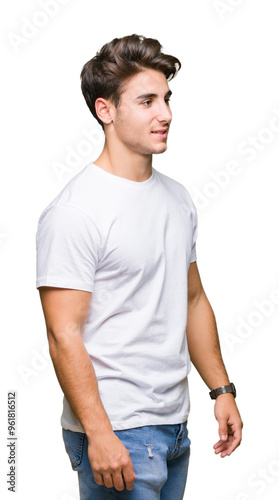 Young handsome man wearing white t-shirt over isolated background looking away to side with smile on face, natural expression. Laughing confident.