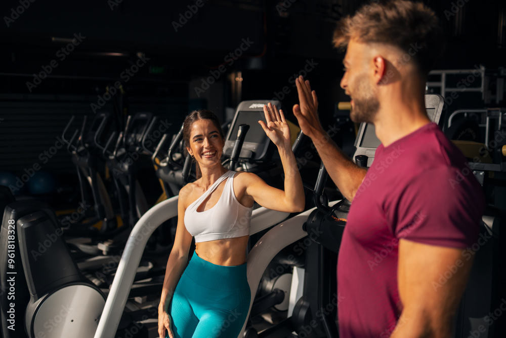 A happy young adult couple high-fiving each other at the gym A happy young adult couple high-fiving each other at the gym