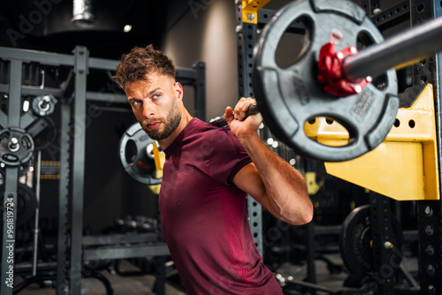 Foto A focused young adult man lifting heavy weights at the gym