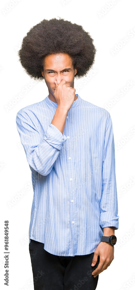 Fototapeta premium Young african american man with afro hair smelling something stinky and disgusting, intolerable smell, holding breath with fingers on nose. Bad smells concept.