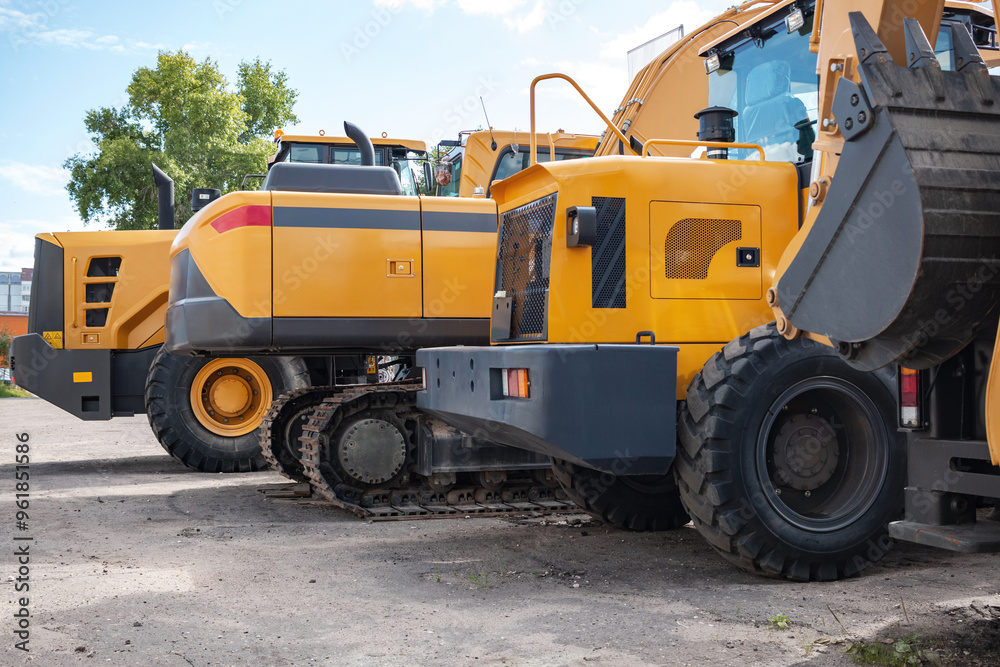 Yellow construction equipment stands in a row. Yellow construction equipment stands in a row.