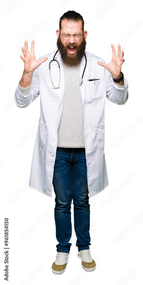 Young blond doctor man with beard wearing medical coat celebrating mad and crazy for success with arms raised and closed eyes screaming excited. Winner concept Young blond doctor man with beard wearing medical coat celebrating mad and crazy for success with arms raised and closed eyes screaming excited. Winner concept