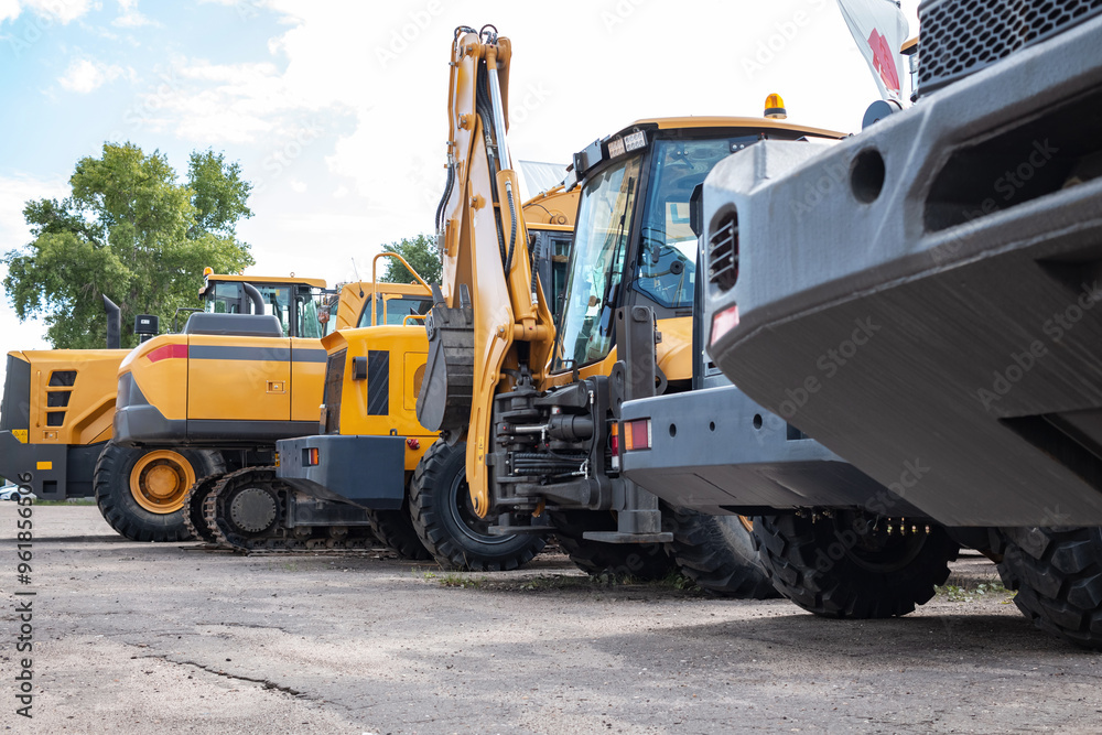 Yellow construction equipment stands in a row. Yellow construction equipment stands in a row.