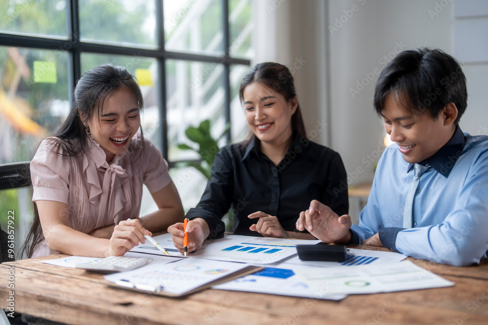 Group of asian business people smiling and having fun while analyzing financial report papers using calculator Group of asian business people smiling and having fun while analyzing financial report papers using calculator