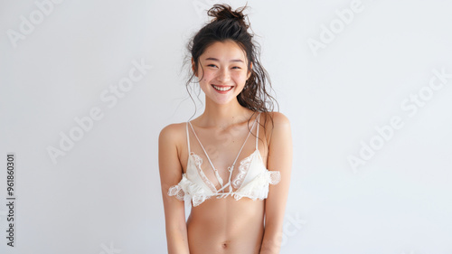 A young woman with a radiant smile poses confidently in a white bikini top. Her carefree expression and flowing hair exude a sense of joy and freedom.