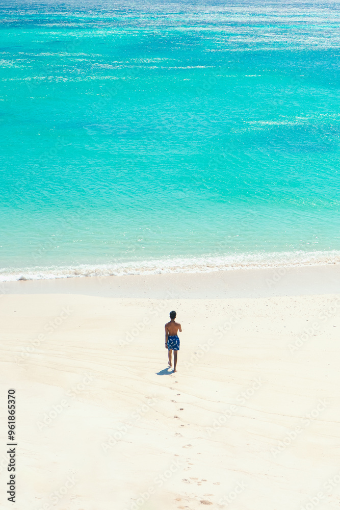 Man traveler walks on beautiful natural white sandy beach and clear blue sea water. summer background and summer holiday concept. Man traveler walks on beautiful natural white sandy beach and clear blue sea water. summer background and summer holiday concept.