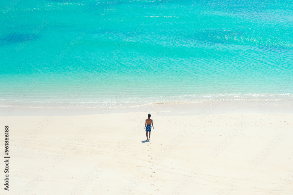 Man traveler walks on beautiful natural white sandy beach and clear blue sea water. summer background and summer holiday concept. Man traveler walks on beautiful natural white sandy beach and clear blue sea water. summer background and summer holiday concept.