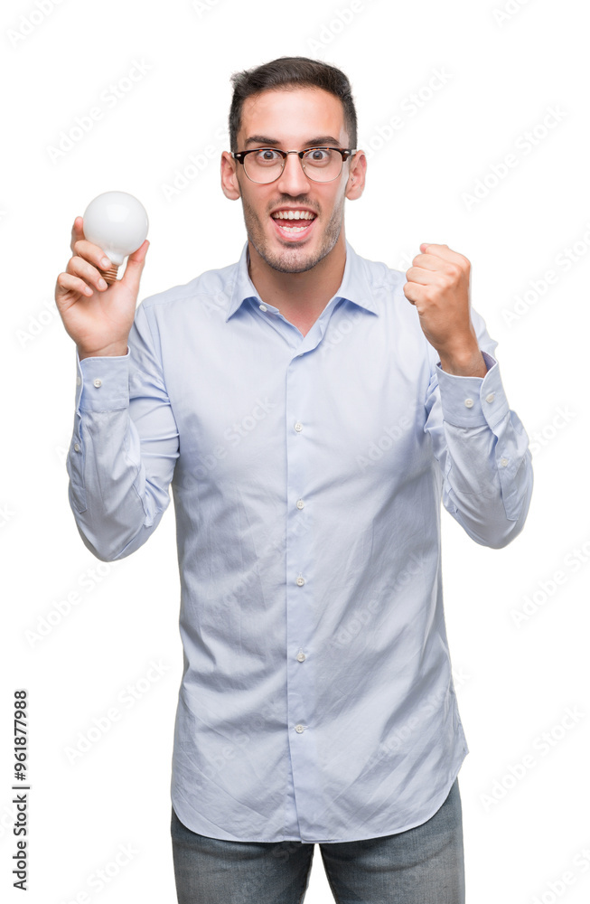 Handsome young man holding lightbulb as idea screaming proud and celebrating victory and success very excited, cheering emotion Handsome young man holding lightbulb as idea screaming proud and celebrating victory and success very excited, cheering emotion