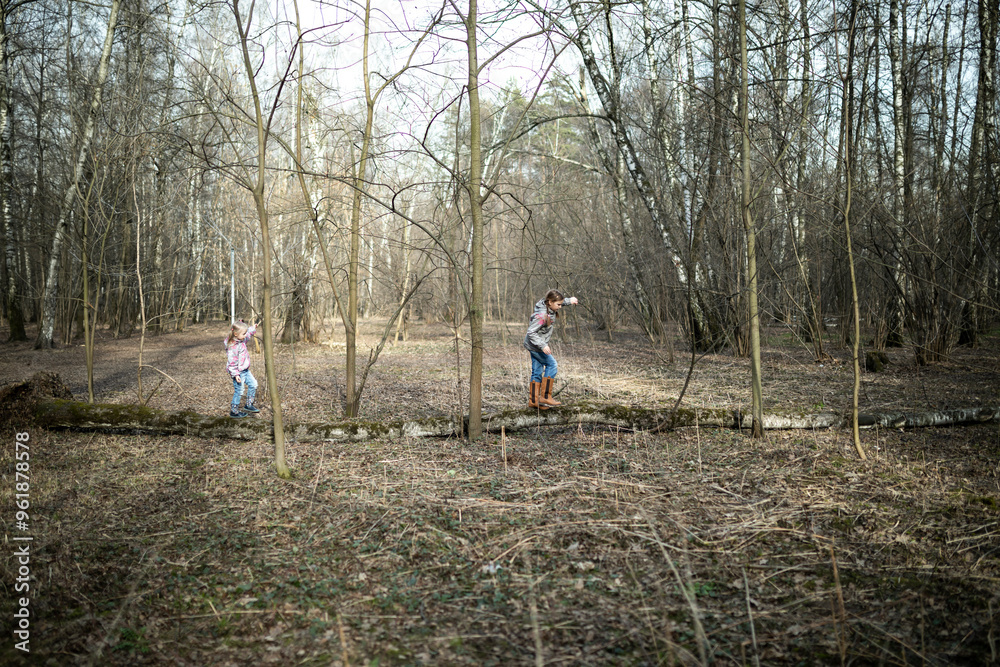 Little girls playing in the forest during the day on a beautiful autumn day. Concept of sisterhood and relationships