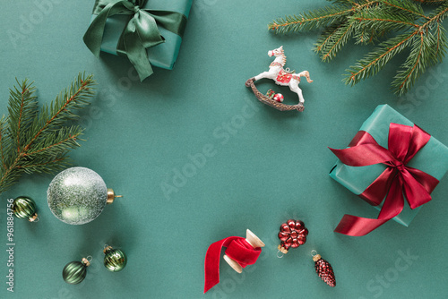 Overhead view of wrapped Christmas gifts, fir branches, Christmas baubles, ornaments and decorations on a green background