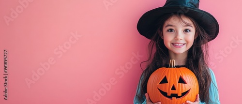 A young girl is holding a pumpkin with a smile on her face