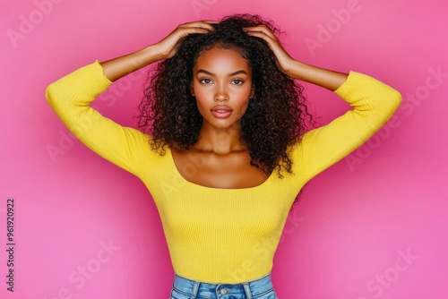 Isolated on pink color background, a young model girl is pouting her lips while kissing her curly hairstyle.