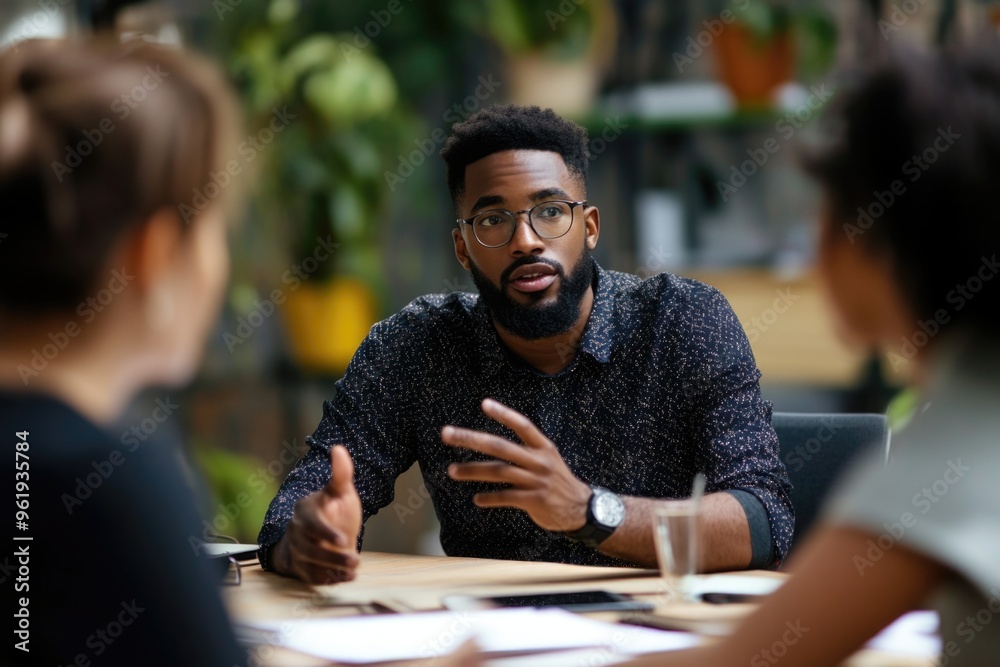 Obraz premium A man with glasses is talking to two other people at a table