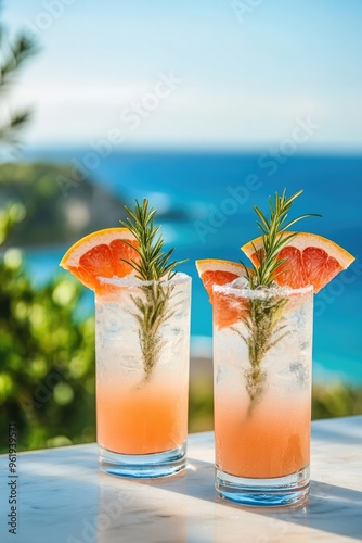 Two Glasses of Grapefruit and Rosemary Mocktail with a Sea View Background