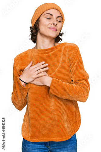 Young hispanic woman wearing casual clothes and wool cap smiling with hands on chest with closed eyes and grateful gesture on face. health concept.