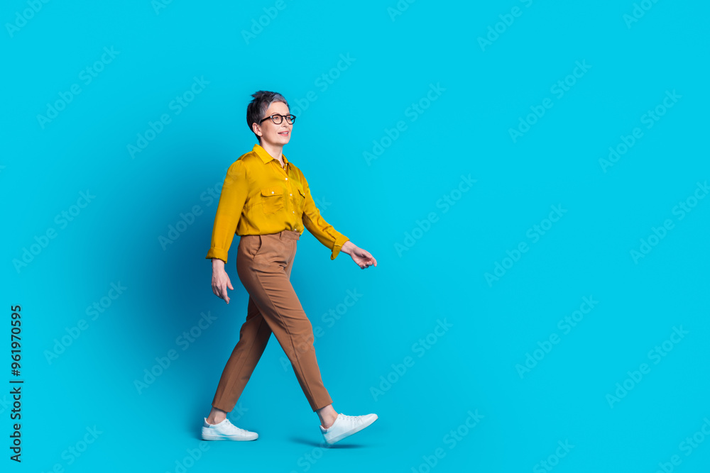 Full length photo of confident attractive lady dressed shirt glasses walking emtpy space isolated blue color background