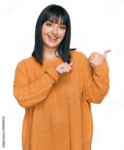 Young hispanic woman wearing casual clothes pointing to the back behind with hand and thumbs up, smiling confident photo