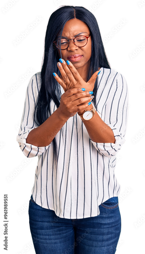 Young african american woman wearing casual clothes and glasses suffering pain on hands and fingers, arthritis inflammation Young african american woman wearing casual clothes and glasses suffering pain on hands and fingers, arthritis inflammation