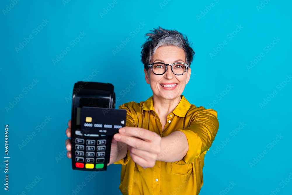 Photo of charming positive woman wear blue blouse eyeglasses smiling paying bank card isolated blue color background Photo of charming positive woman wear blue blouse eyeglasses smiling paying bank card isolated blue color background