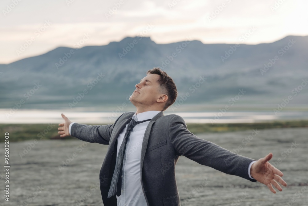 Man open arms mountains. Businessman in suit standing on a beach with his arms outstretched, embracing the natural beauty of the mountains. Man open arms mountains. Businessman in suit standing on a beach with his arms outstretched, embracing the natural beauty of the mountains.