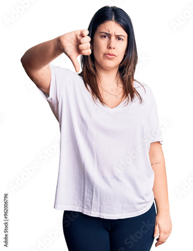 Young beautiful brunette woman wearing casual t-shirt looking unhappy and angry showing rejection and negative with thumbs down gesture. bad expression.