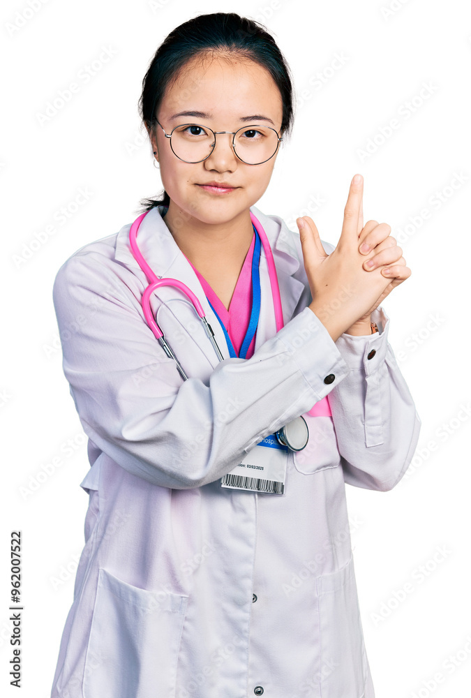Young chinese woman wearing doctor uniform and stethoscope holding symbolic gun with hand gesture, playing killing shooting weapons, angry face Young chinese woman wearing doctor uniform and stethoscope holding symbolic gun with hand gesture, playing killing shooting weapons, angry face