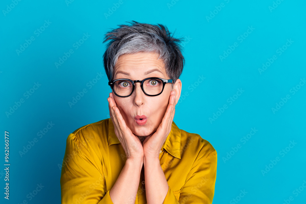 Photo of adorable shockes lady dressed shirt eyewear arms cheeks empty space isolated blue color background Photo of adorable shockes lady dressed shirt eyewear arms cheeks empty space isolated blue color background