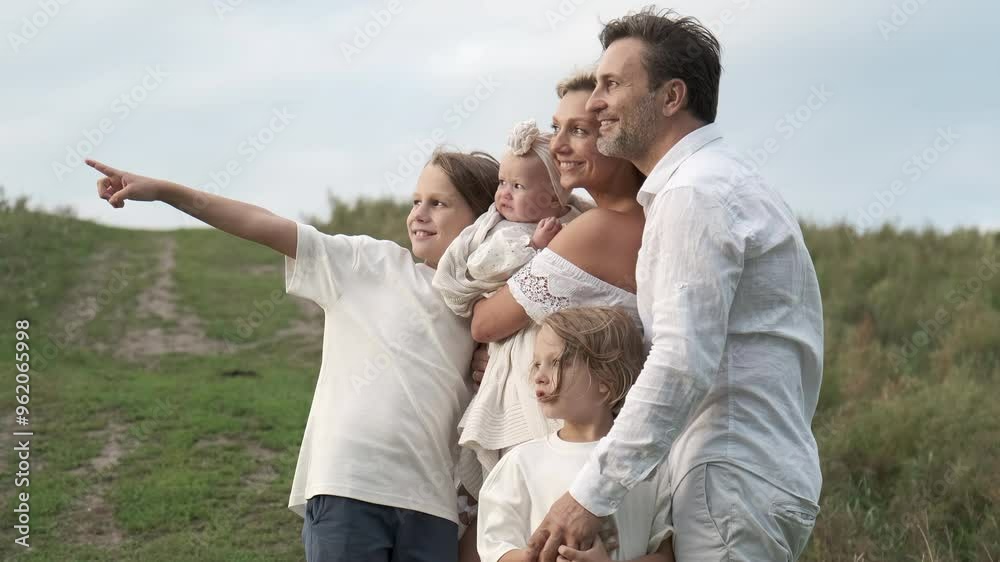 A family stands on a lawn and points into the distance.