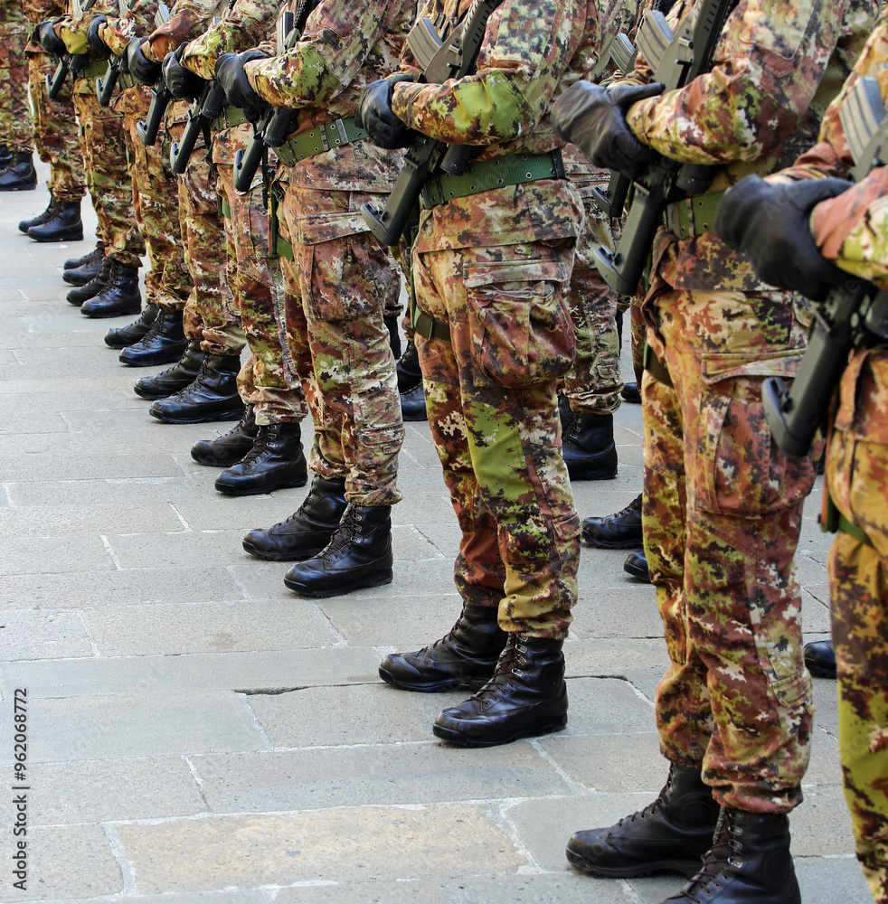 Black combat boots of army soldiers in camouflage uniforms standing in formation Black combat boots of army soldiers in camouflage uniforms standing in formation
