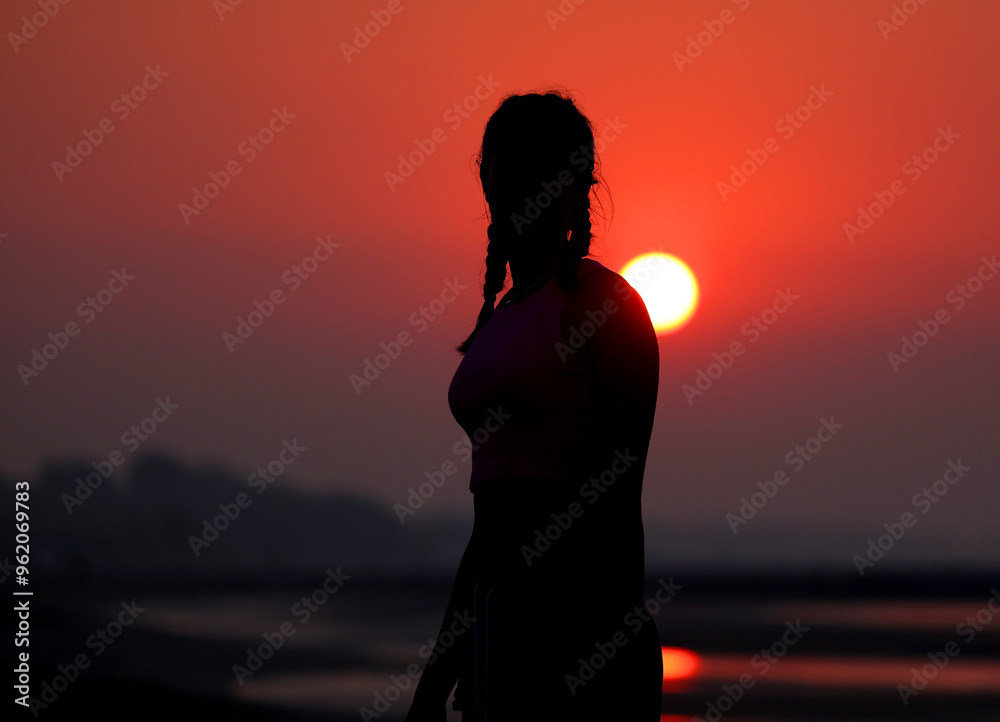 silhouette of young girl with braids backlit with sun behind her silhouette of young girl with braids backlit with sun behind her