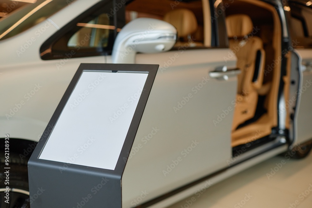 Car dealership information stand with blank mockup sheet displaying vehicle specifications in showroom, copy space