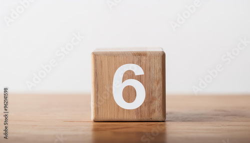 Wooden cube with number 6 on wooden table, white wall on background. Event planner, calendar