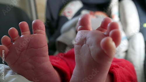 Close-up of baby’s tiny feet, soft and tender toes, relaxed infant in car seat, cozy and calm atmosphere, detailed view of newborn’s feet, intimate and loving moment, peaceful and comfortable rest photo