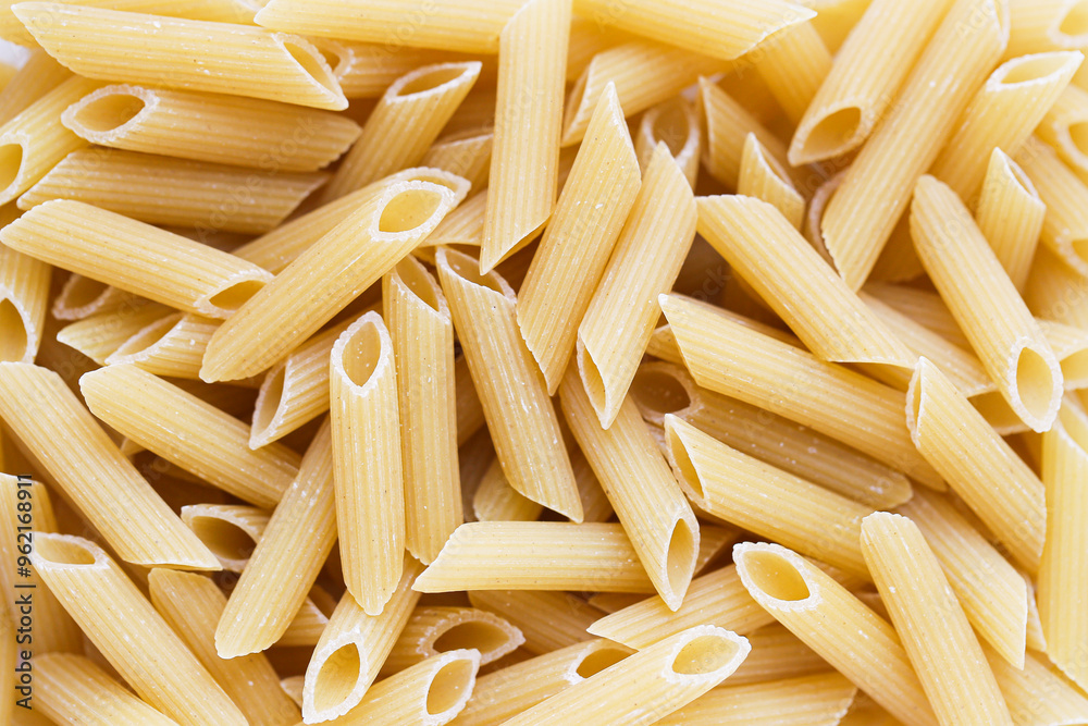 Yellow penne pasta texture. A detailed view capturing the ridges and structure of uncooked penne. Vibrant closeup macro shot of food. Italian cusine pattern. Yellow penne pasta texture. A detailed view capturing the ridges and structure of uncooked penne. Vibrant closeup macro shot of food. Italian cusine pattern.