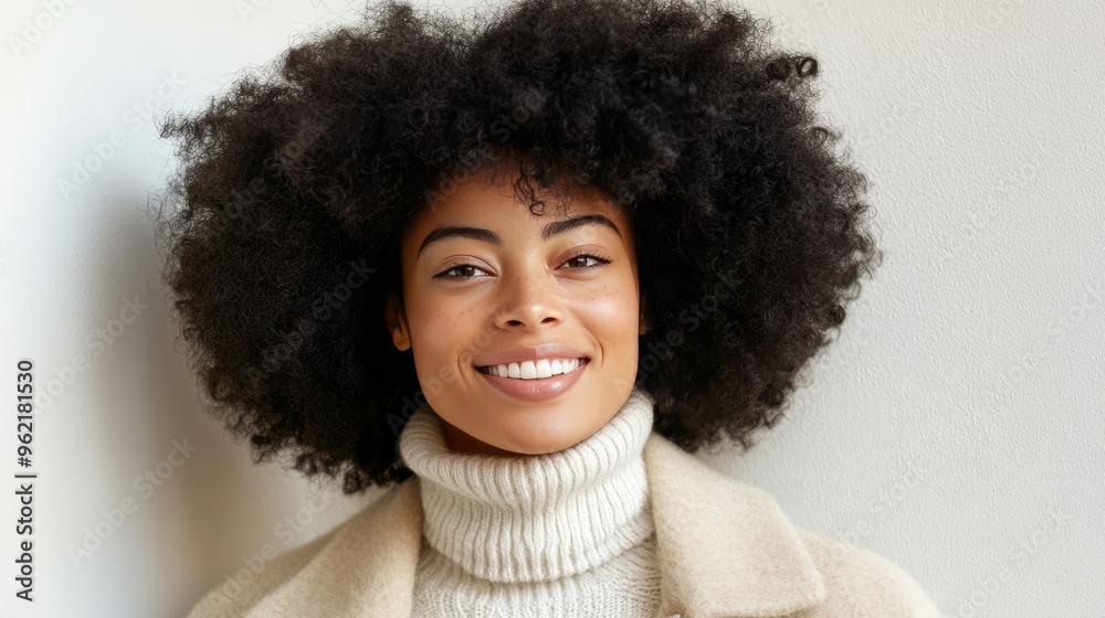 Smiling woman with afro hair wearing a white turtleneck sweater and a beige jacket. Smiling woman with afro hair wearing a white turtleneck sweater and a beige jacket.