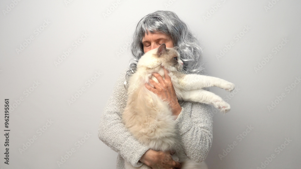 Obraz premium A mature woman with gray hair hugs a cat.