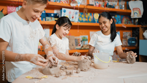 Caucasian highschool girl modeling cup of clay while looking smart boy in art class at workshop. Multicultural student playing or making cup of clay art in creative activity. Education. Edification.