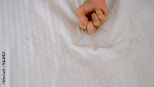 Woman holding man's hand lying in bed making love, hands close-up. Sex, intimate life, pleasure and love concept. Two lovers having a sex holding hands, sensual gesture.