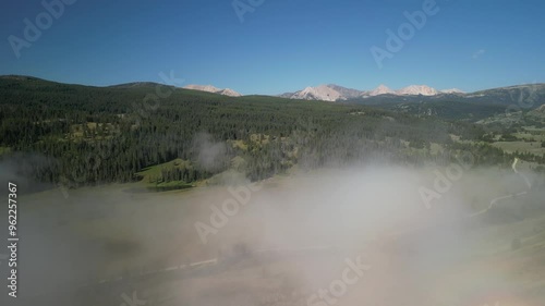 Aerial through low clouds above meadow in Montana Madison Range in early morning summer photo