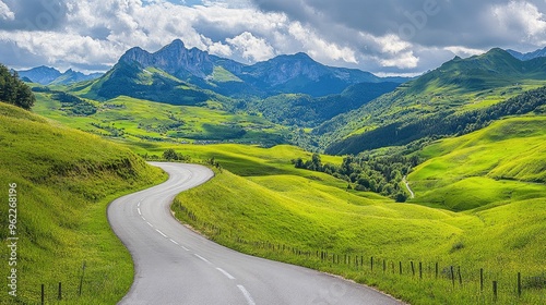 Wide view of a picturesque, winding road through a lush green landscape with scenic mountains in the distance photo