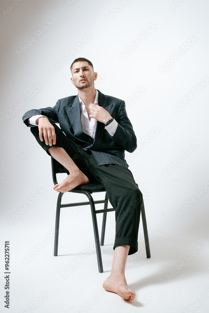 Handsome man, fashion model sits on chair, barefoot Handsome man, fashion model sits on chair, barefoot