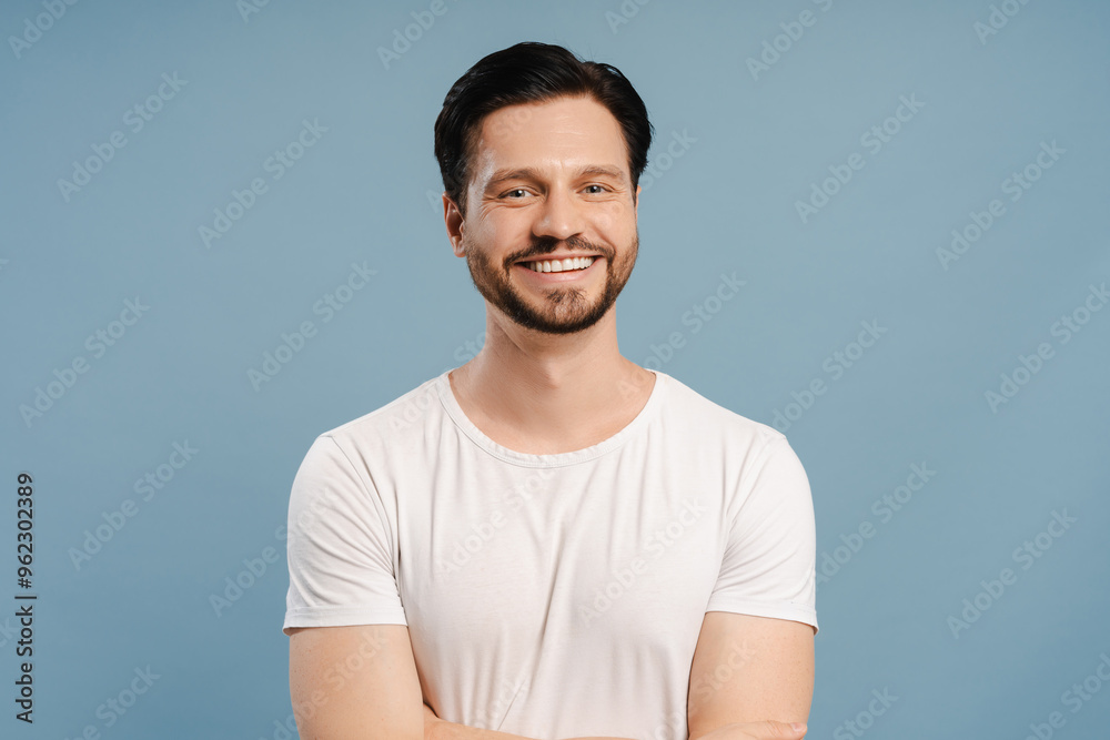 Handsome young man with beard smiling. looking at camera, isolated on blue background Handsome young man with beard smiling. looking at camera, isolated on blue background