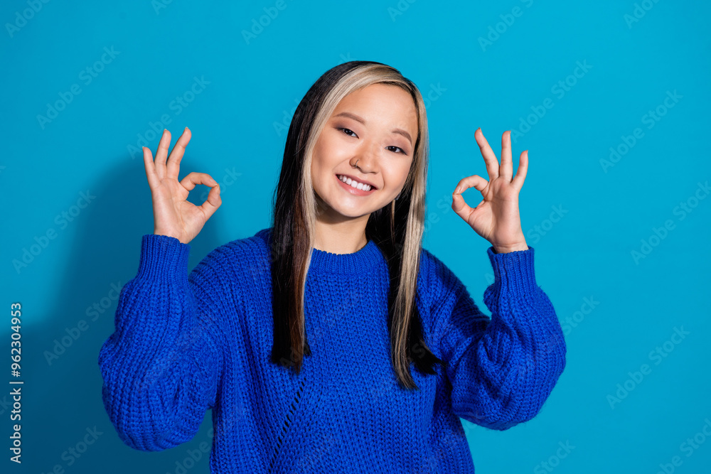Photo portrait of lovely young lady okey approve dressed stylish knitwear garment isolated on blue color background Photo portrait of lovely young lady okey approve dressed stylish knitwear garment isolated on blue color background