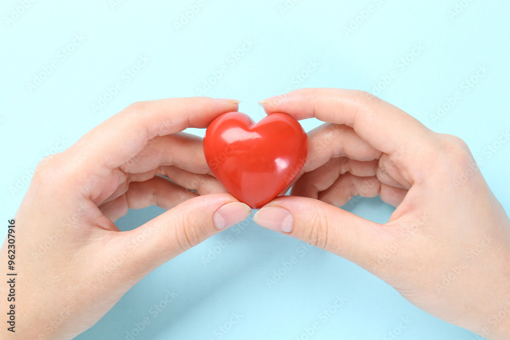 Obraz premium Woman with red heart on light blue background, closeup