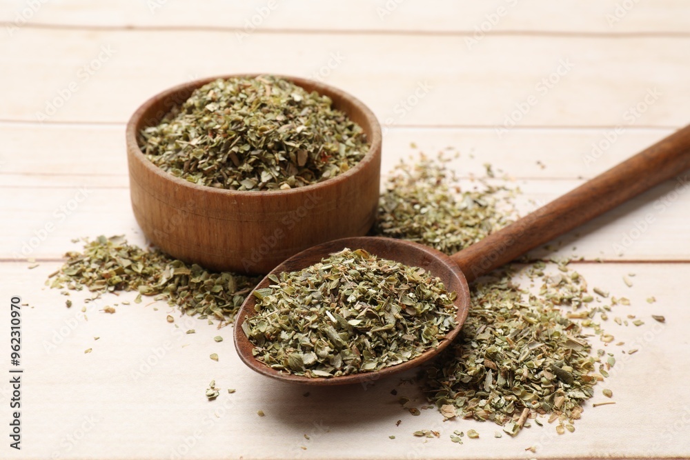 Dried oregano in spoon and bowl on wooden table, closeup Dried oregano in spoon and bowl on wooden table, closeup