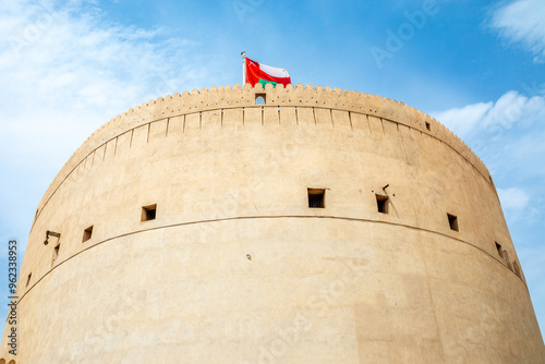 Main tower of Nizwa arabic citadel fortress with Omani flag waving on top, Nizwa, sultanate Oman photo