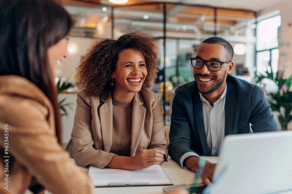 Joyful young couple engaging with a female real estate agent in a professional office setting Joyful young couple engaging with a female real estate agent in a professional office setting