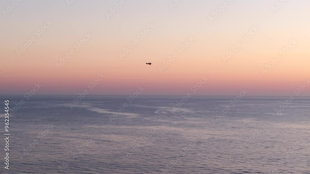 Aerial view following a small plane flying up the coast of La Jolla at sunset with colorful orange and red sky reflecting off the Pacific Ocean in Southern California Aerial view following a small plane flying up the coast of La Jolla at sunset with colorful orange and red sky reflecting off the Pacific Ocean in Southern California
