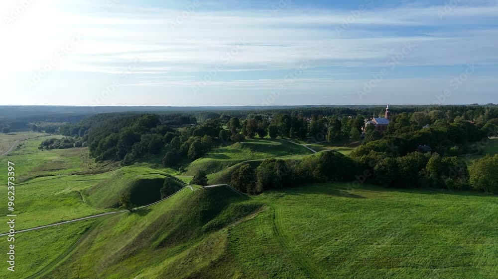 Aerial view of Kernave mounds, historical site in Lithuania. Aerial view of the Kernave mounds, an ancient archaeological site in Lithuania, surrounded by green hills and nature. Aerial view of Kernave mounds, historical site in Lithuania. Aerial view of the Kernave mounds, an ancient archaeological site in Lithuania, surrounded by green hills and nature.