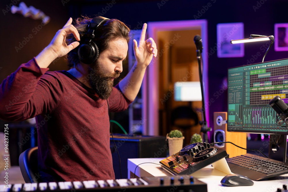 Φωτογραφία Cheerful confident artist listening to new song on headphones, doing mix and master before launching music in home studio